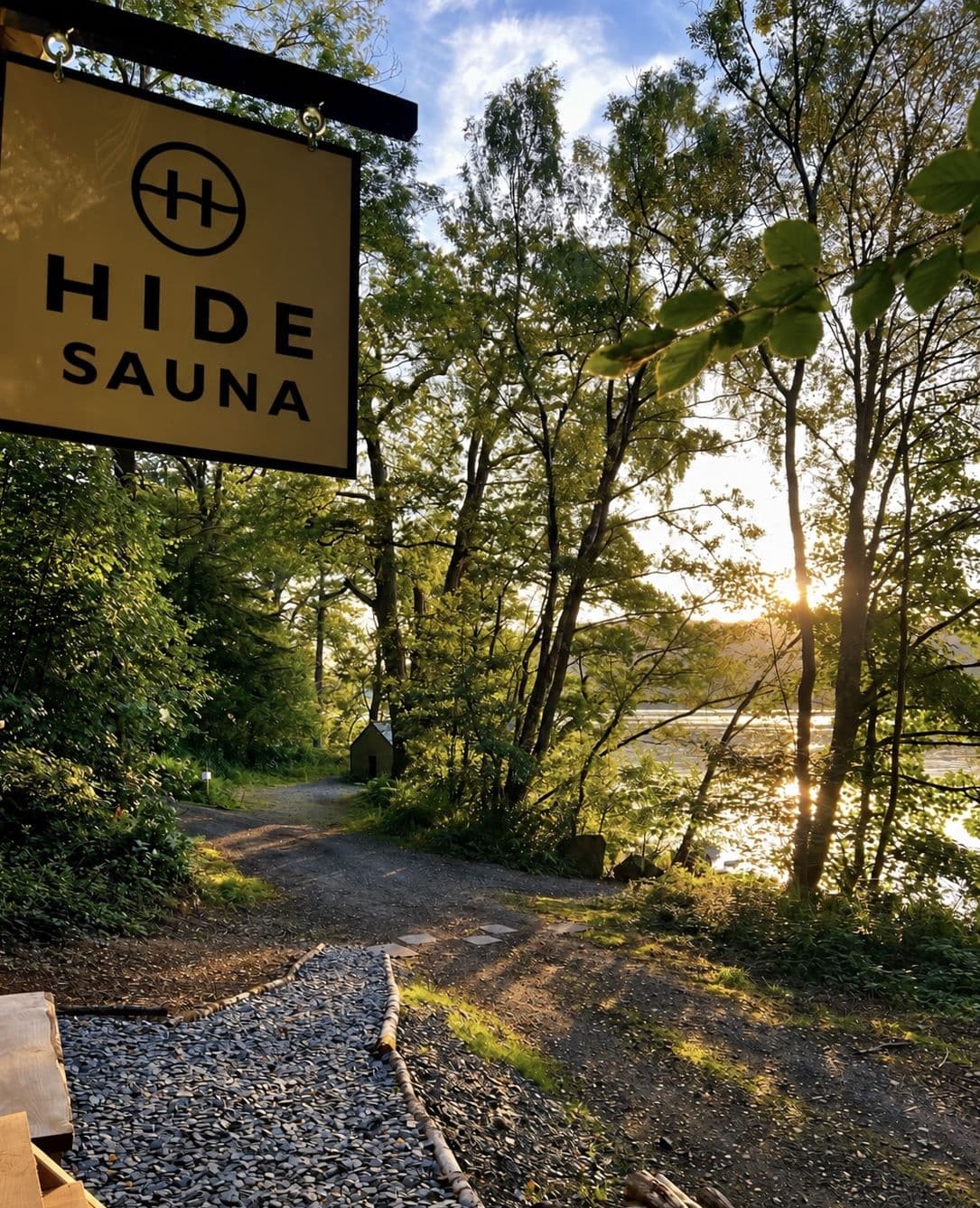 Evening sun through the lakeside trees onto Windermere, a gravel path leading along the shore past a small hut